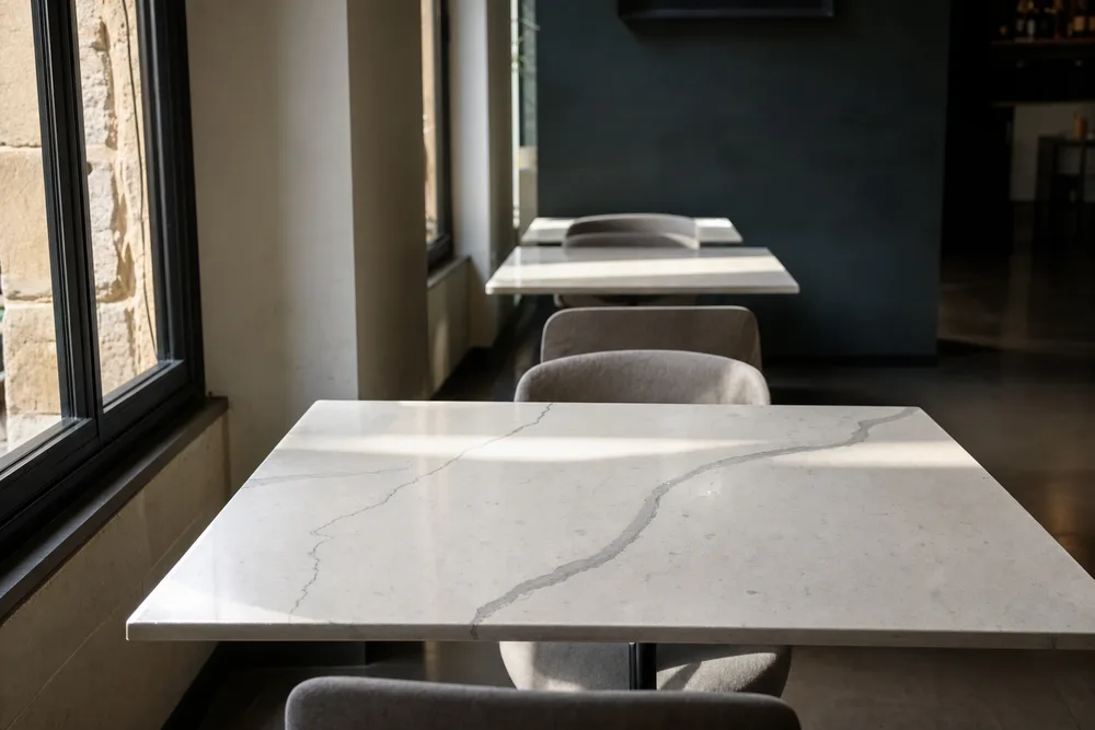 Stone-topped restaurant tables beside a window